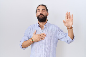 Hispanic man with beard wearing casual shirt swearing with hand on chest and open palm, making a...