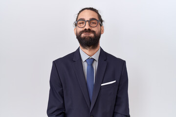 Hispanic man with beard wearing suit and tie puffing cheeks with funny face. mouth inflated with air, crazy expression.