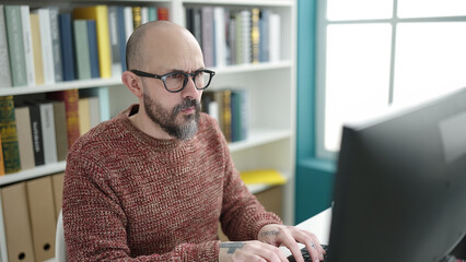 Young bald man student using computer studying at university classroom
