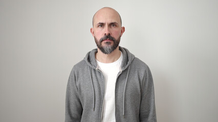 Young bald man standing with serious expression over isolated white background