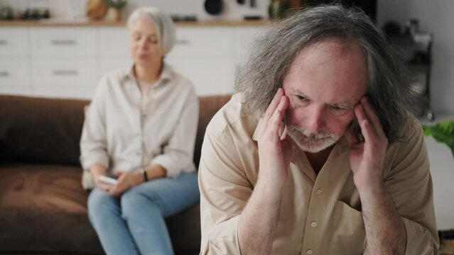 problems in family relationships in an elderly couple, family crisis. An elderly couple in a living room sit without talking to each other, holding a grudge