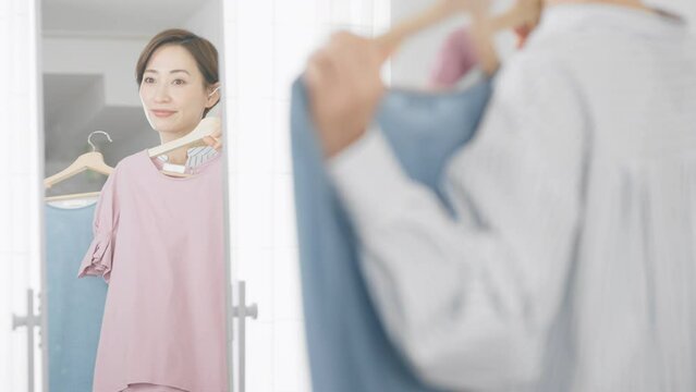 鏡の前で服選びをしている若い女性　ファッションイメージ	