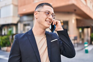 Young hispanic man executive smiling confident talking on smartphone at street