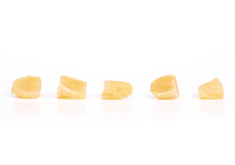 Isolated candied ginger pieces in a row. Yellow chunks of candied or crystallized ginger. Healthy snack for helping with digestive system, motion sickness and immunize system. Selective focus.