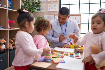 Hispanic man and girls having lesson at kindergarten