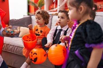 Group of kids wearing halloween costume eating candies at home