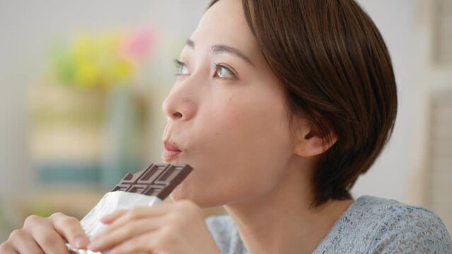 チョコレートを食べる若い女性　飲食イメージ