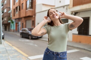 Young beautiful woman listening to music and dancing at street