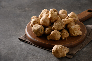 Raw Jerusalem artichoke root, sunchokes in wicker basket on brown background. Close up.