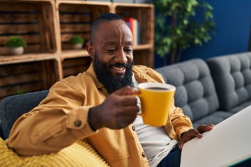 Young african american man reading book and drinking coffee at home