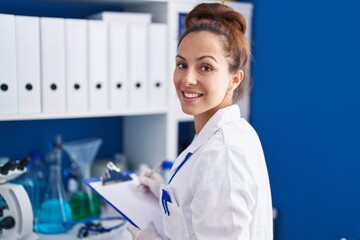 Young woman scientist writing on document working at laboratory