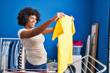 African american woman smiling confident hanging clothes on clothesline at laundry room - Powered by Adobe