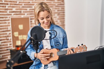 Young blonde woman musician singing song playing ukelele at music studio