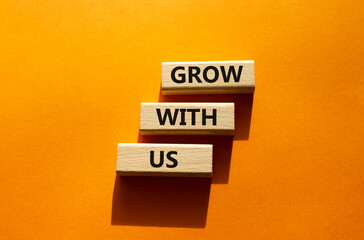 Grow with us symbol. Wooden blocks with words Grow with us. Beautiful orange background. Business and Grow with us concept. Copy space.
