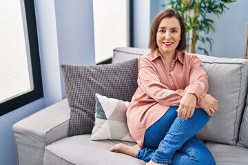 Obraz premium Middle age woman smiling confident sitting on sofa at home