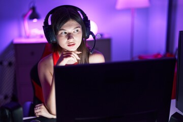 Young caucasian woman streamer sitting on table with serious expression at gaming room
