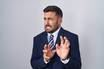 Handsome hispanic man wearing suit and tie disgusted expression, displeased and fearful doing disgust face because aversion reaction.