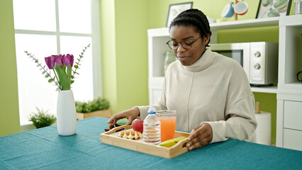 Fototapeta premium African american woman having breakfast sitting on table at dinning room