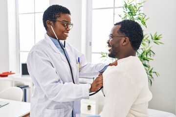 Man and woman doctor and patient having medical consultation auscultating chest at clinic