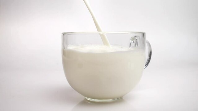 Milk pouring into a glass on a white background slow motion