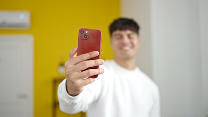 Young hispanic man make selfie by camera standing at home
