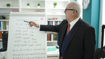senior teaching maths on magnetic board at university classroom
