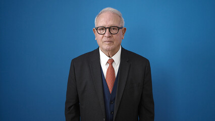 senior standing with serious expression over isolated blue background