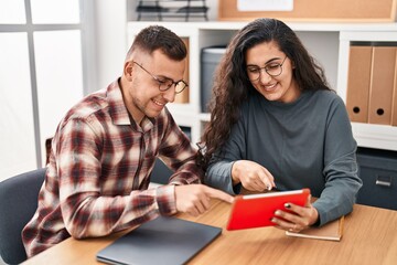 Man and woman business workers using laptop and touchpad at office