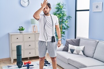 Handsome latin man wearing sportswear at home surprised with hand on head for mistake, remember...