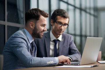 Obraz premium Two handsome businessmen working together on a project sitting