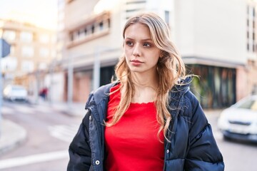 Fototapeta na wymiar Young blonde woman looking to the side with serious expression at street