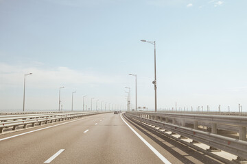 Automobile bridge across the Kerch Strait or Crimean bridge. Asphalt road with marking and road lampposts with alarm annunciators.
