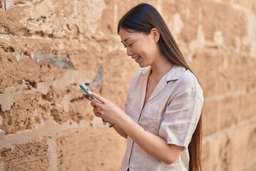 Chinese woman smiling confident using smartphone at street