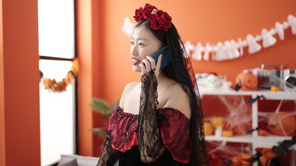 Young chinese woman wearing katrina costume talking on smartphone at home