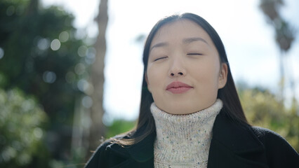 Young chinese woman breathing with closed eyes at park