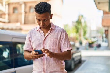 Young latin man using smartphone at street