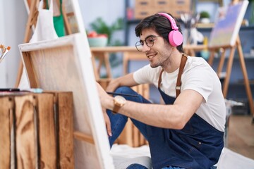 Young hispanic man artist listening to music drawing at art studio