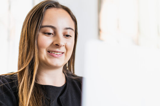 Pretty Twenty Year Old Woman Smiling As She Does Her Work In Front Of The Computer