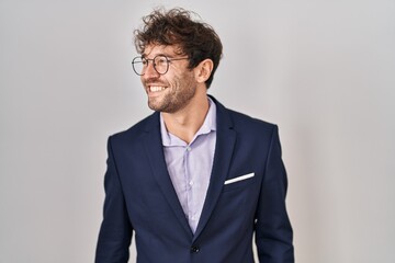 Hispanic business man wearing glasses looking away to side with smile on face, natural expression. laughing confident.