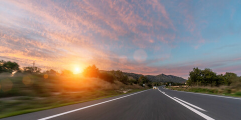 Mediterranean sea coast road into mountains horizon in summer with beautiful bright sun rays. long exposure high speed motion blur shot