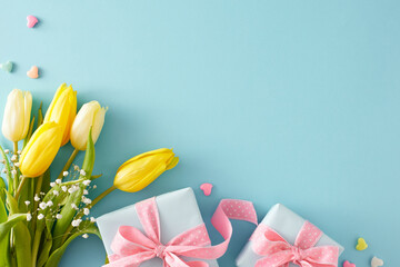 Flat lay photo of gift boxes with bows small hearts baubles bouquet of yellow white tulips and gypsophila flowers on pastel blue background with empty space. Mother's Day celebration concept