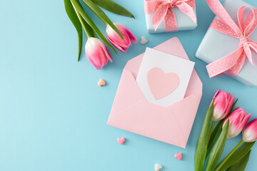 Happy Mother's Day concept. Flat lay photo of open envelope with card gift boxes colorful hearts and pink tulips flowers on pastel blue background with empty space
