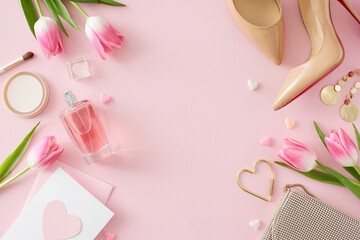 Women's Day mood concept. Flat lay photo of trendy woman shoes perfume cosmetic brush bijouterie earrings handbag postcard and tulips on isolated pastel pink background with empty space in the middle