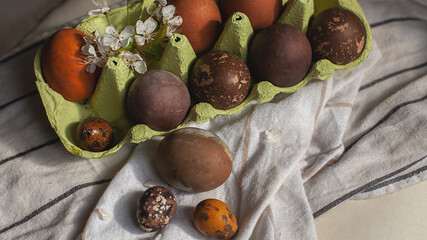 Easter painted eggs and twigs of flowering trees, white flowers of an apple tree. On a rustic eco background made of linen and cardboard. easter village concept