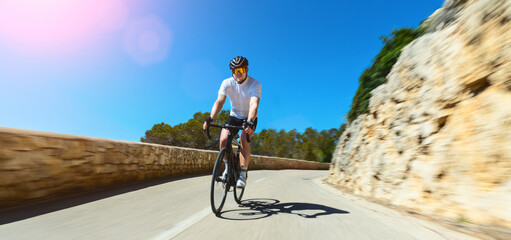Man Adult on a racing bike climbing the hill at mediterranean sea landscape coastal road on...