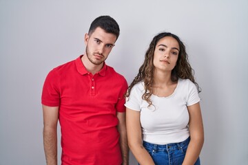 Young hispanic couple standing over isolated background looking sleepy and tired, exhausted for fatigue and hangover, lazy eyes in the morning.