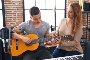 Man and woman musicians having classic guitar lesson at music studio