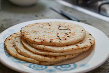 Yellow round arepas on white plate blue decorations with small burnt black dots simple small kitchen