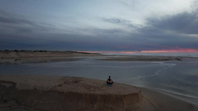 Yoga-style meditation during the sunset on the Moliets beach peninsula next to the Courant d'Huchet Nature Reserve