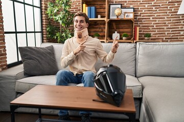 Obraz premium Young man wearing cervical collar for motorbike accident smiling and looking at the camera pointing with two hands and fingers to the side.